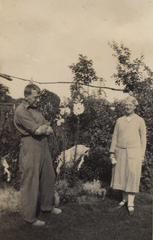 Woman and man with big trousers, in a garden.